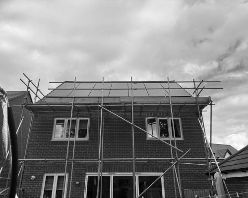 Property under construction with solar panels and scaffolding